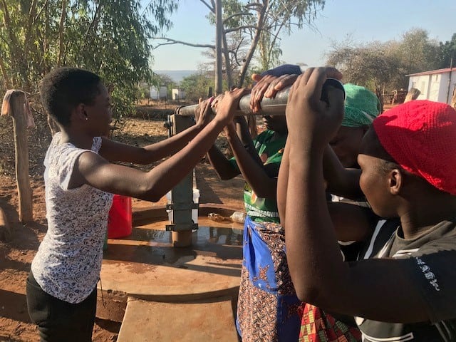 People working together to life a heavy pole