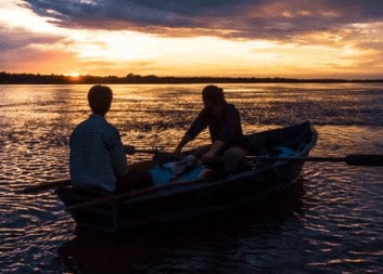 Silhouettes of two men rowing a boat in the Paraguay River